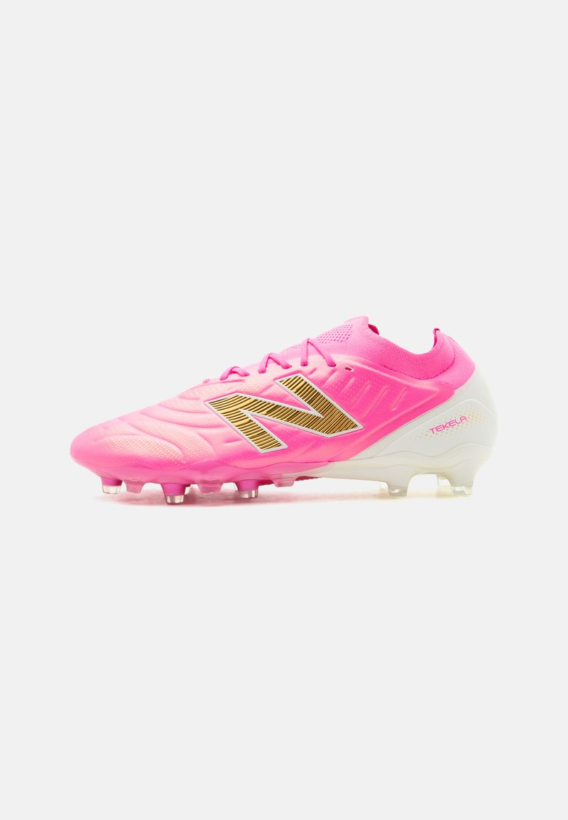 Chaussure de football New Balance Tekela rose vif avec logo "N" doré et semelle blanche à crampons, vue de côté sur fond blanc.