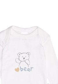 White long-sleeve onesie made of cotton, featuring a gray sketch of a bear and blue text "bear" with a brown heart accent.