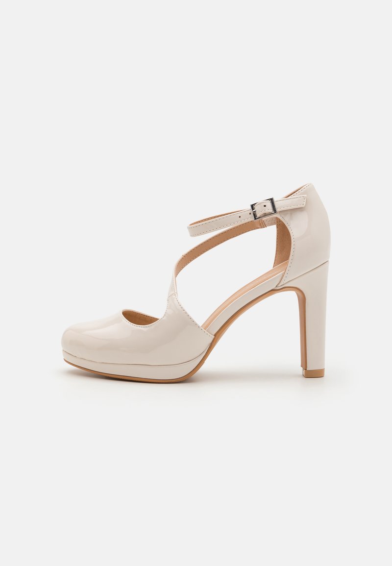 Pale beige patent leather high-heeled shoe with a rounded toe, cutout design, and ankle strap featuring a silver buckle.