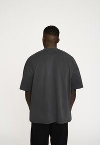 Grå oversized t-shirt med kort ærmer og rund hals, lavet af blødt bomuldsstof, med et enkelt design og ingen synlige mønstre.