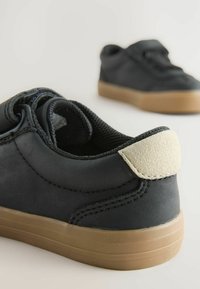 Czarne sneakersy z teksturowaną skórzaną cholewką i jasnoszarym zamszowym akcentem na pięcie, z gumową podeszwą i przeszyciami.