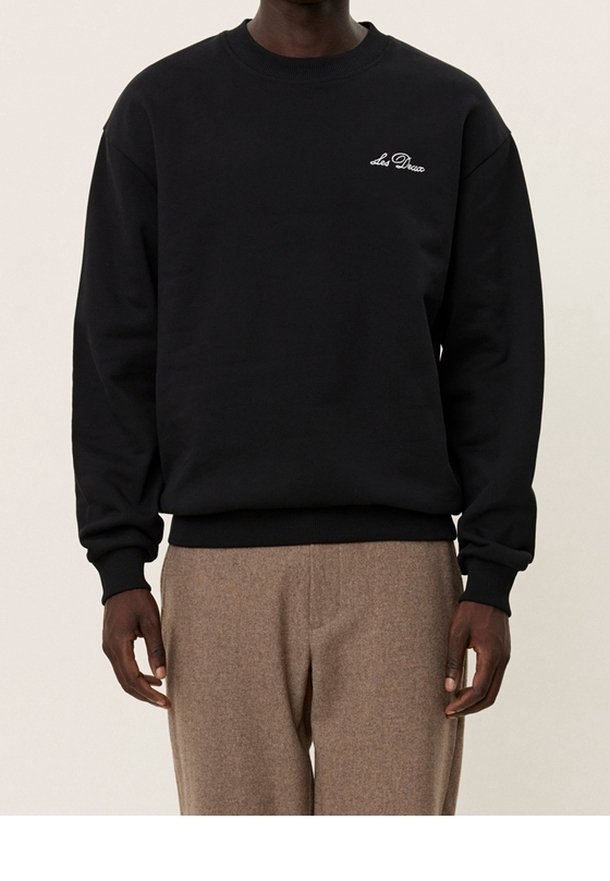 Zwarte sweatshirt van zacht materiaal, met een ronde hals en ribgebreide manchetten. Klein wit geborduurd logo op de borst, relaxte pasvorm.