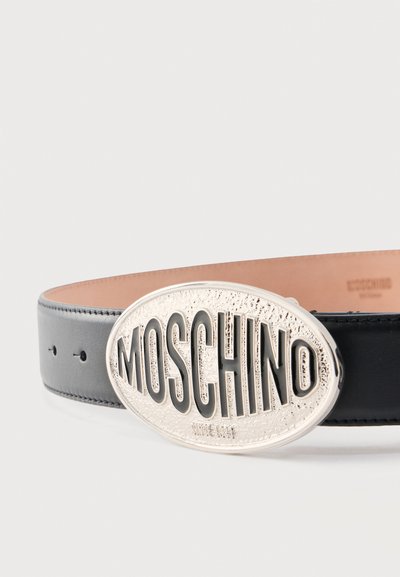 Ceinture en cuir noir avec une grande boucle ovale en argent ornée du lettrage "MOSCHINO" en relief.