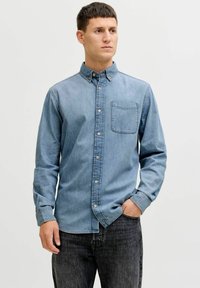 Hellblaues Jeanshemd mit einem Button-Down-Kragen, einer einzelnen Brusttasche und langen Ärmeln; strukturiertes Gewebe mit legerer Passform.
