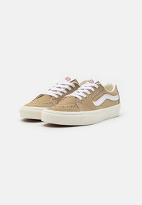 Sneaker in suede marrone con lacci bianchi e suole in gomma. Presentano una striscia laterale in pelle bianca e dettagli in cucitura.