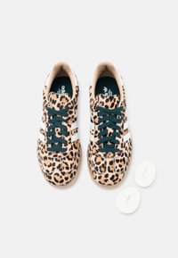 Tenisky s leopardím vzorem a zelenými tkaničkami, s bílými pruhy, měkkou strukturou a kontrastními krémovými akcenty. Součástí jsou i extra bílé tkaničky.