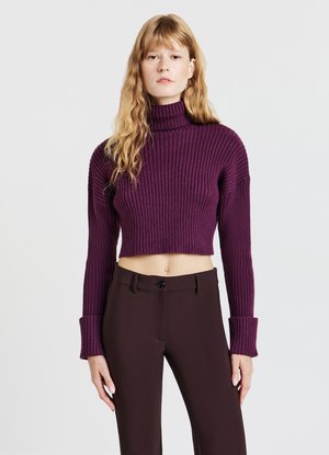 Maglione a collo alto a coste, tagliato, di un profondo viola, con maniche lunghe dotate di ampi polsini, abbinato a pantaloni sartoriali marrone scuro.