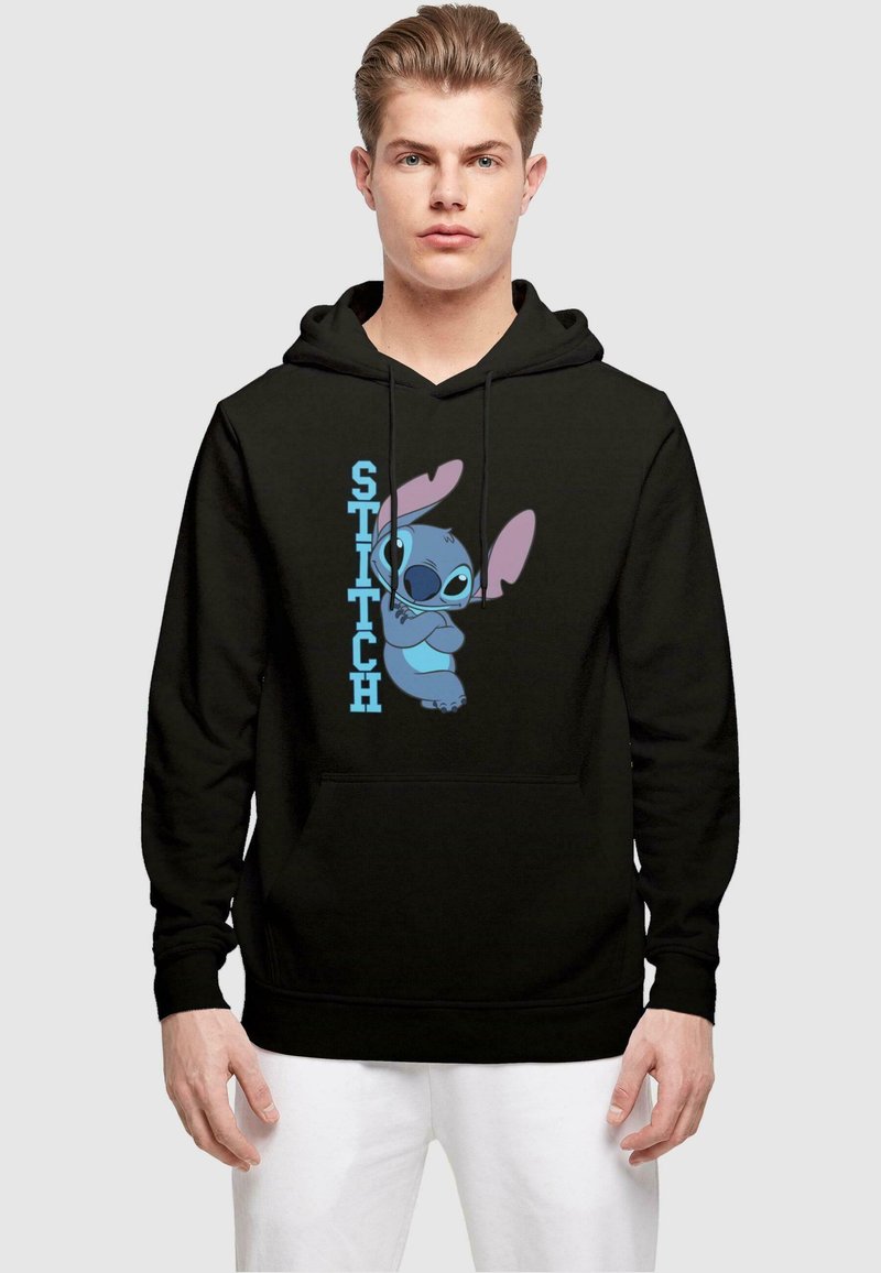 Svart hettegenser med grafisk trykk av Stitch, en blå tegneseriefigur, og teksten "STITCH" i lys blå på venstre side.