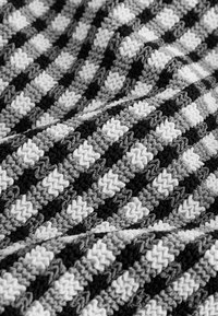 Tekstureret stof med et zigzag-mønster i sort, hvidt og nuancer af gråt. Materialet har et vævet udseende med skiftende farvebånd.