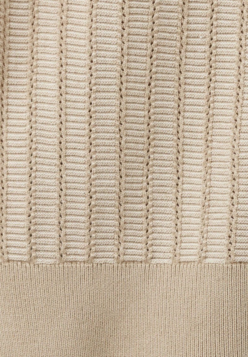 Tissu tricoté beige avec des rayures verticales côtelées et ajourées, passant à une section lisse et étroitement tricotée en bas.