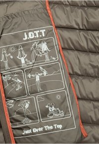 Gewatteerde binnenkant van het jack in donkerbruin met witte illustraties die verschillende buitenactiviteiten tonen en de tekst "Just Over The Top." Oranjekleurige accenten.