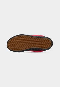 Semelle extérieure en caoutchouc présentant une surface brune texturée et à motifs avec un bord noir, des bords incurvés et une partie supérieure rose vif.