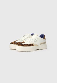 White sneaker with leopard print accents, textured upper, and a chunky sole. Features a padded collar and lace-up closure.