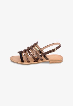 Brown strappy sandal with multiple cross straps, featuring a mix of smooth and textured materials, flat sole, and adjustable ankle strap.