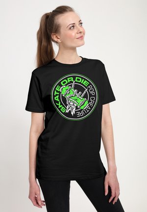 Sort t-shirt med et levende grønt og hvidt grafisk design, der viser et skateboardmotiv med teksten "SKATE OR DIE" iøjnefaldende.