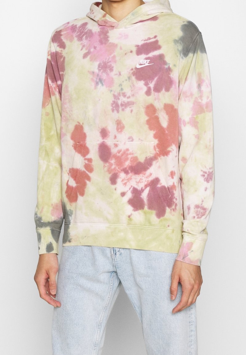 Mikina s kapucí ve stylu tie-dye s kombinací růžové, zelené a šedé barvy, s přední kapsou a malým bílým logem Nike na hrudi.