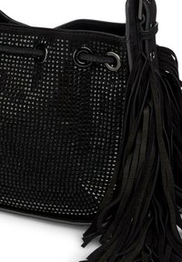 Borsa a secchiello in pelle intrecciata nera con dettagli di occhielli e lunghe frange testurizzate su un lato. Piccole accentuazioni metalliche lucide arricchiscono il design.