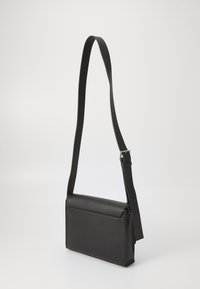 Borsa a tracolla nera in pelle texturizzata, con forma rettangolare, tracolla regolabile e design minimalista.