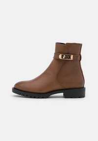 Bottines en cuir marron avec un bout arrondi, accent de boucle et semelle en caoutchouc texturé. Fini lisse et semelle noire contrastante.