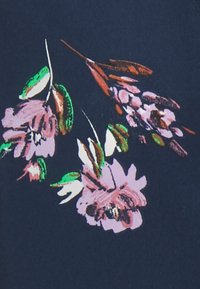 Motivo floreale su tessuto blu navy, con fiori rosa e foglie verdi. Il design include pennellate variegate e dettagli di texture.