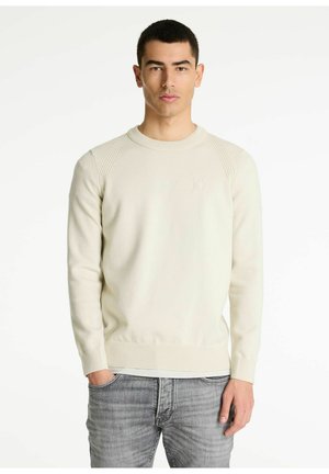 Suéter beige claro hecho de una tela suave, con un escote redondo, puños acanalados y un logo sutil en el pecho.