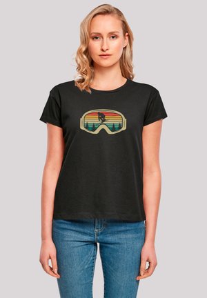 Black t-shirt featuring a colorful graphic of ski goggles with a silhouette of a skier and trees against a gradient sunset background.
