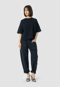 Navy blue oversized t-shirt with short sleeves, paired with navy blue loose-fit cargo pants featuring pockets, worn with grey heels.