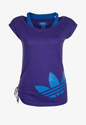 Paarse Adidas T-shirt met blauw trefoil-logo aan de voorkant, samengebonden zijkantstrik en een blauwe tanktop eronder.