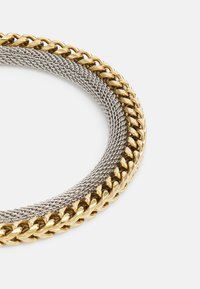Collana in oro e argento con anelli alternati piatti e rotondi. Texture liscia con una finitura lucida, creando un effetto a strati.