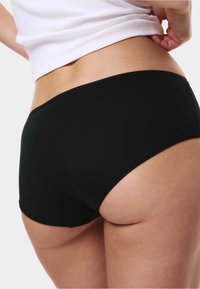 Černé šortky s vysokým pasem, vyrobené z hladké látky, s bezešvým designem a minimálním šitím podél okrajů pro pohodlí.