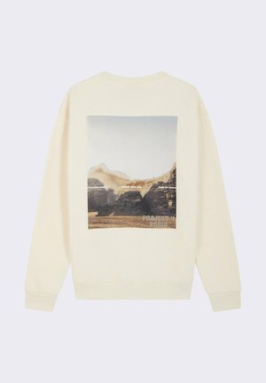 Sweatshirt créme avec une impression graphique d'un paysage au dos. Le design présente un col rond et des poignets côtelés.