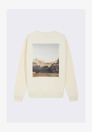Sweatshirt créme avec une impression graphique d'un paysage au dos. Le design présente un col rond et des poignets côtelés.