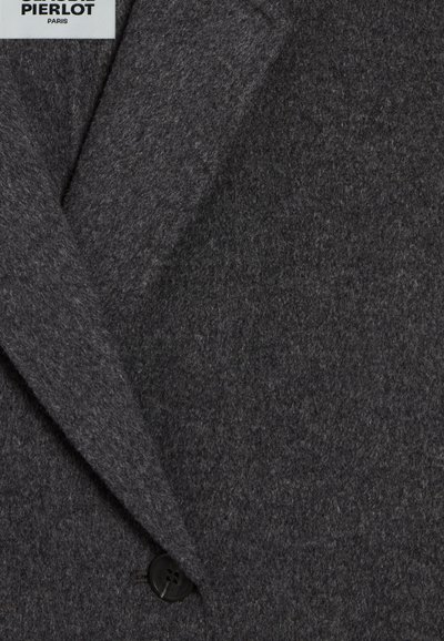 Blazer en laine grise avec col cranté, présentant une texture lisse et une fermeture à un seul bouton noir. Design minimaliste et lignes épurées.