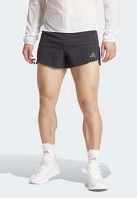 Zwarte hardloopshorts met een gestructureerd ontwerp en een zijslit, gecombineerd met witte sokken en hardloopschoenen. Geaccentueerd door een zilveren logo.