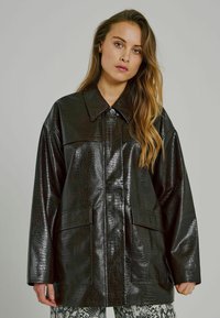 Must must nahk-efekti suur jakk, millel on tekstuuriga krokodillnaha muster. Omab teravat kraed ja kahte esikotti.