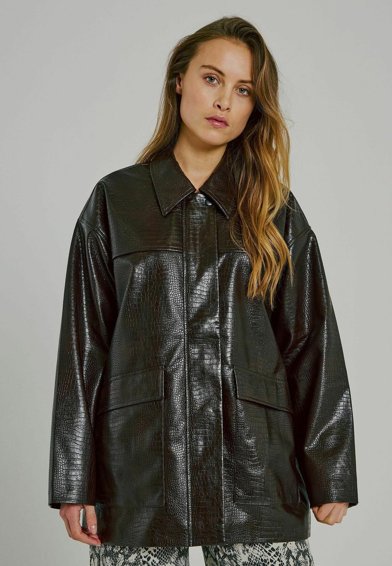 Must must nahk-efekti suur jakk, millel on tekstuuriga krokodillnaha muster. Omab teravat kraed ja kahte esikotti.