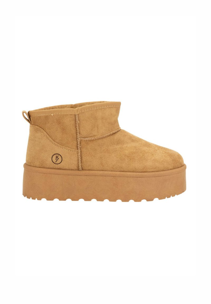 Botines de ante en tono beige con puntera redondeada, perfil bajo y suela de plataforma texturizada. Cuenta con un logo lateral y una lengüeta para facilitar el poner y quitar.