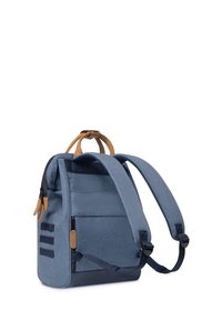 Zaino in tessuto blu con accenti in pelle marrone, forma rettangolare, spallacci ergonomici e tasca anteriore con zip e dettagli testurizzati.