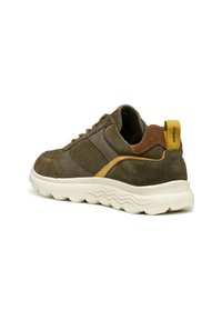 Sneaker in suede verde oliva con dettagli marroni, un tallone giallo e una suola bianca spessa caratterizzata da motivi ondulati. Design con lacci.