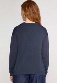 Pull en tricot côtelé navy à manches longues, col rond et coupe décontractée. Texture subtile avec des manches à poignets et un ourlet droit.
