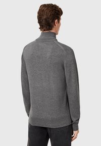 Grijze trui met nepbodem en lange mouwen, geribde manchetten en zoom. Heeft een gladde textuur en naadloze schouders.