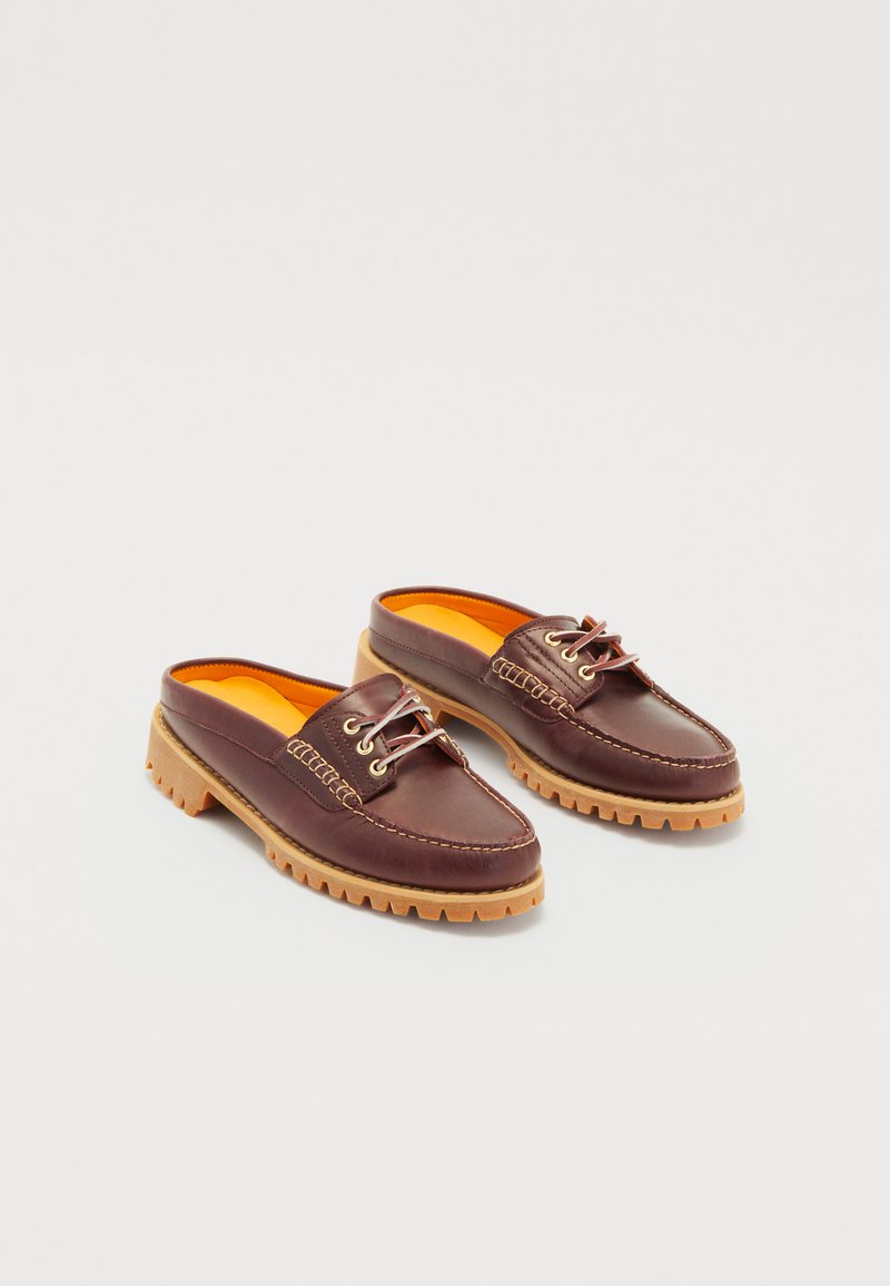 Scarpe slip-on in pelle marrone con lacci, suola in gomma e soletta arancione. Presentano dettagli di cucitura e un design in stile mocassino.