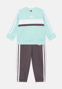 Sudadera verde menta con rayas horizontales blancas y gris oscuro, combinada con pantalones de chándal grises que tienen rayas laterales blancas. Tejido de mezcla de algodón.