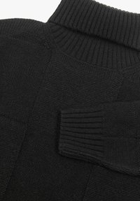 Suéter negro de punto con un alto cuello acanalado, diseño de panel texturizado y un bolsillo sin costuras en la parte delantera.