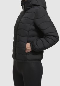 Czarna kurtka puchowa z kapturem, z pikowanej tkaniny, z zamkiem błyskawicznym i elastycznymi mankietami. Zawiera boczne kieszenie do przechowywania.