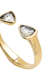 Anillo de oro con banda partida, que presenta dos piedras preciosas triangulares transparentes. Acabado liso con superficie pulida y engastes de garras.