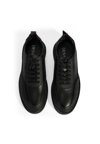 Sneakers en cuir noir avec une tige texturée, un bout rond et des lacets plats. Accentuées par une languette et un détail de doublure contrastante.