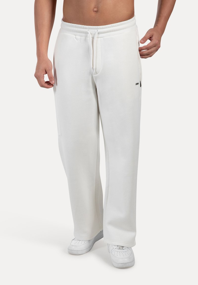 Pantalones de chándal blancos hechos de tela suave, con cintura elástica y cordón, bolsillos laterales y un corte relajado.
