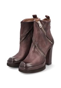 Botas de tobillo de cuero marrón oscuro con un acabado suave, con cremalleras diagonales y tacones altos y gruesos. Punta redondeada y suela resistente.