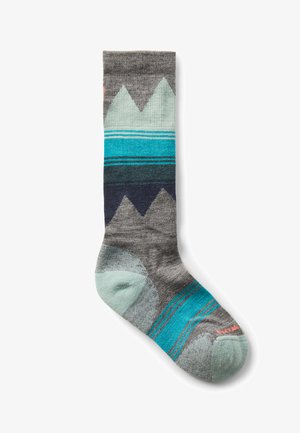 Calzini alti fino al ginocchio in grigio con motivi montani in teal e navy. Presentano una punta e un tallone azzurri, realizzati in materiale morbido e testurizzato.